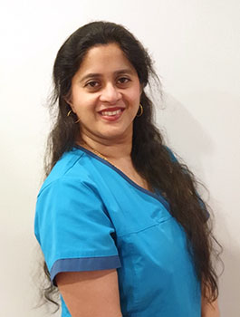 Dr Senthini Ganesvaran wearing blue scrubs smiling at the camera